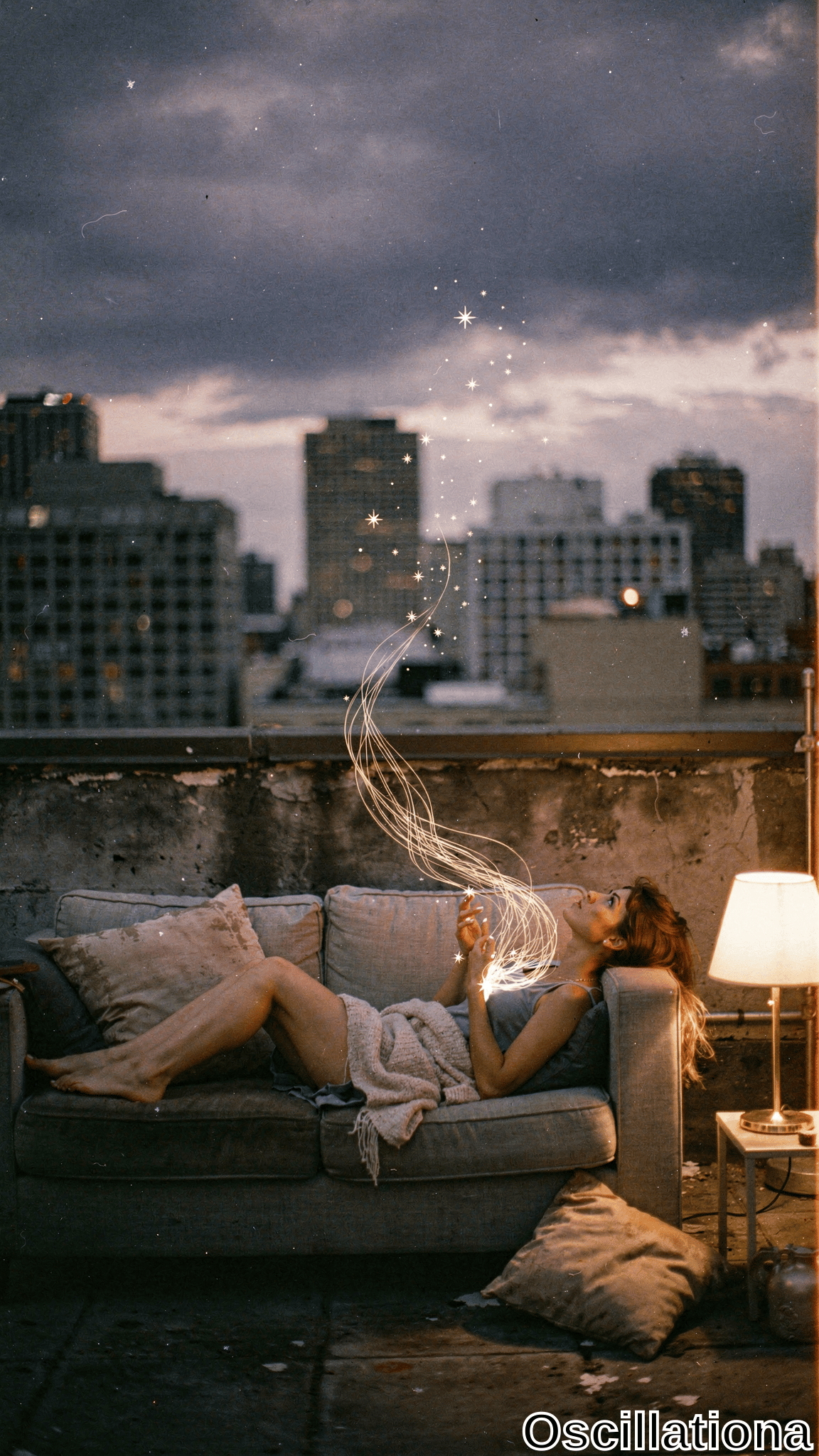 Dreamy twilight rooftop: young woman with long wavy auburn hair lounges barefoot on weathered beige sofa in gray tank & knit sweater, hand aloft emitting swirling golden light trails & stars. Purple-blue sky, city skyline, pillows