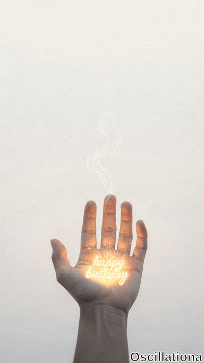 A human hand holds its palm upward, displaying glowing 'happy birthday' text with sparkling particles and thin smoke rising from the fingers against a plain light background.